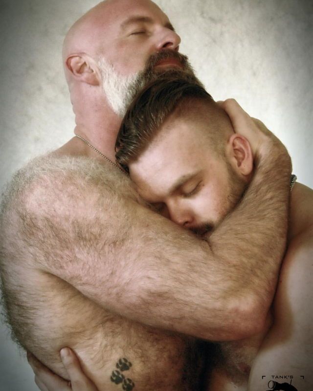 Hombre maduro y peludo abraza a un hombre joven afectivamente.
